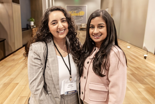 Two attendees posing together, smiling towards the camera.